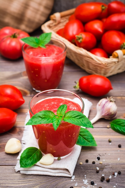 Blended fresh tomato juice with basil leaves in glasses  on a wooden table