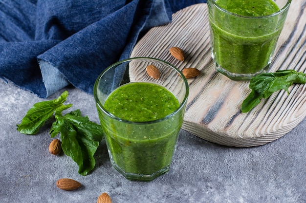 Blended Green Smoothie with green apple, spinach, kiwi and almond nuts on gray concrete background. 