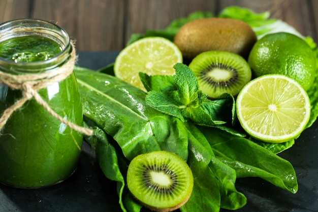 Blended green smoothie with ingredients on the stone board, wood