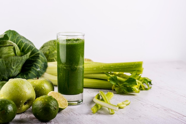 Blended green smoothie with ingredients on wooden table. Dexox drink.