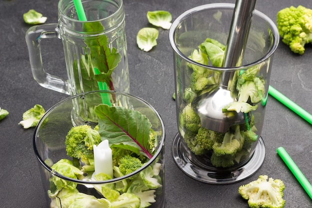 Blender bowl  with broccoli and chard leaves.