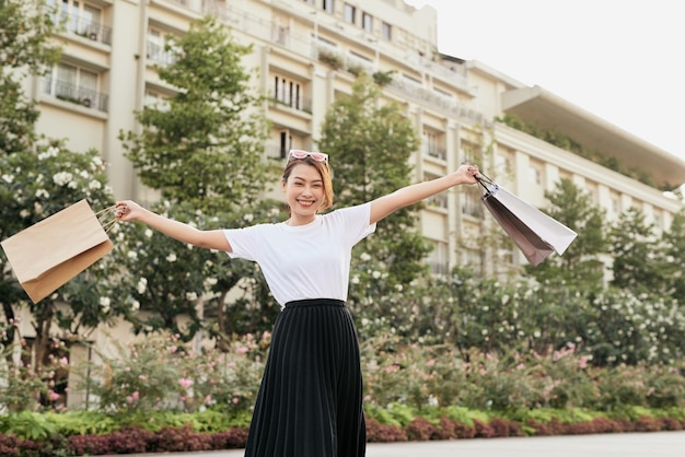 Blissful shopaholic woman dancing on the street with smile