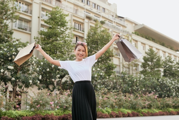 Blissful shopaholic woman dancing on the street with smile.