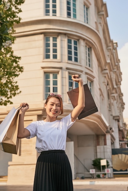 Blissful shopaholic woman dancing on the street with smile.