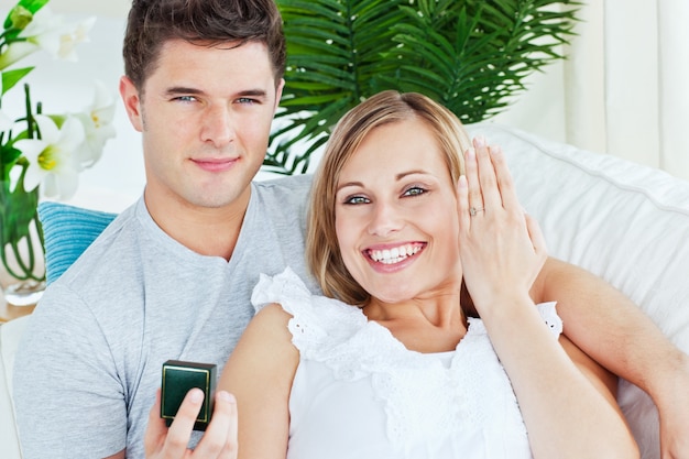 Blissful woman showing her wedding ring to the camera lying with her boyfriend