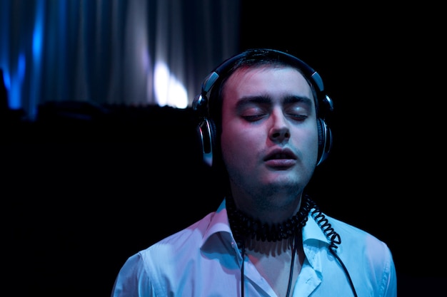 Blissful young man enjoying the music standing listening to his headphones with his eyes closed