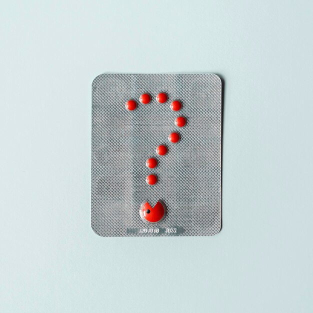 Photo blister with red pills in the shape of a question creative pharmaceutical concept