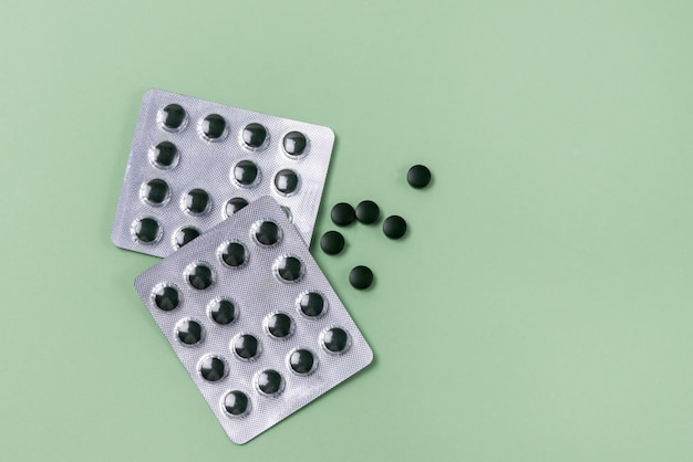 Blisters of Spirulina Tablets on Green Background Super Food Horizontal