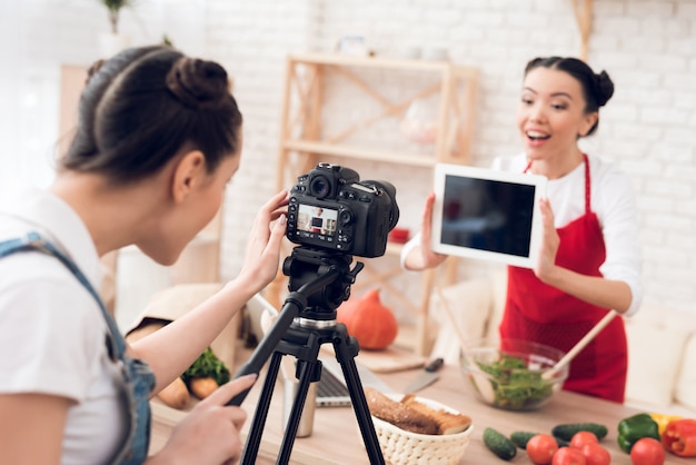 Blogger girl holds up blank tablet to camera.