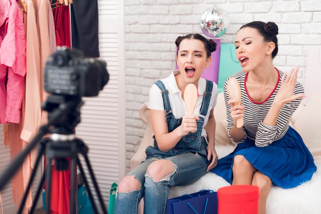 Blogger girls hold up combs singing to camera.