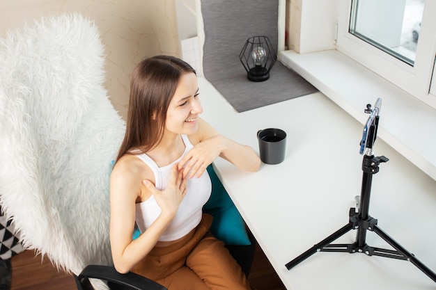 Blogger a modern profession for teenagers a girl at home in front of a smartphone tells stories to the camera for the audience