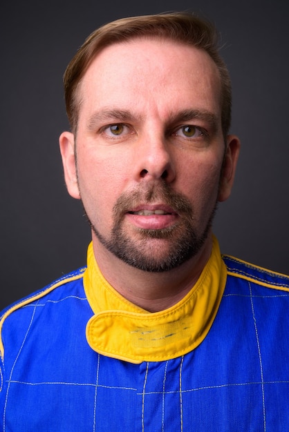 blond bearded man motorcyclist with goatee in full gear on gray