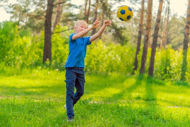 Blond boy in a blue Tshirt throwing the ball in the park