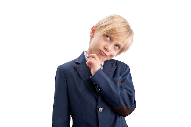 Blond boy in school uniform is thinking about something and looking up Portrait of primary school student isolated on white background