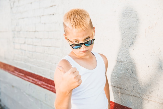 Photo blond boy in a white t-shirt with sunglasses on his head. close-up portrait