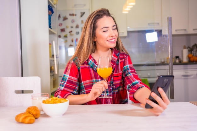 Blond Caucasian woman having a fresh orange juice for breakfast in her kitchen