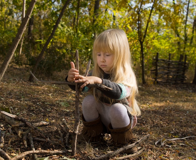 Blond Girl Concentrating While Building Stick Structure Outdoors in Autumn