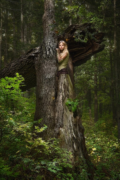 Blond girl dressed in dress walk in a magic forest