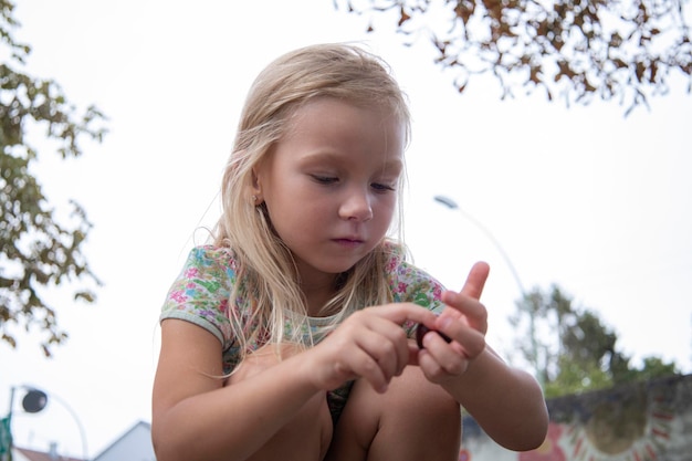 Photo blond girl of preschool age is played holding a pebble in her hands top view flat lay