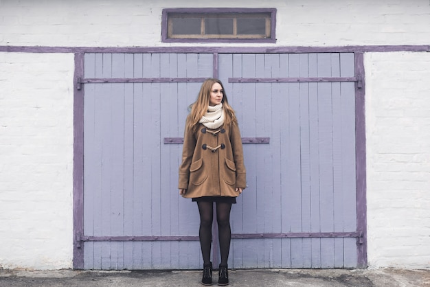 Blond-haired young girl cheerful joyful dressed you in a beige coat and white scarf