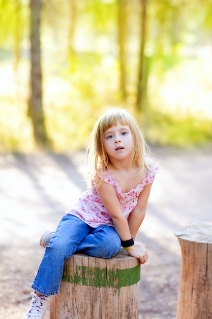 blond kid girl in tree trunk forest