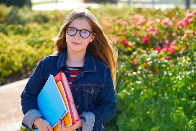 Blond kid student girl in the park with glasses