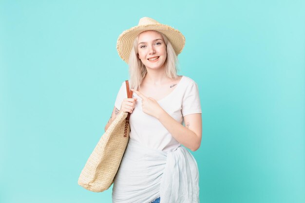 Blond pretty woman smiling cheerfully, feeling happy and pointing to the side. summer concept