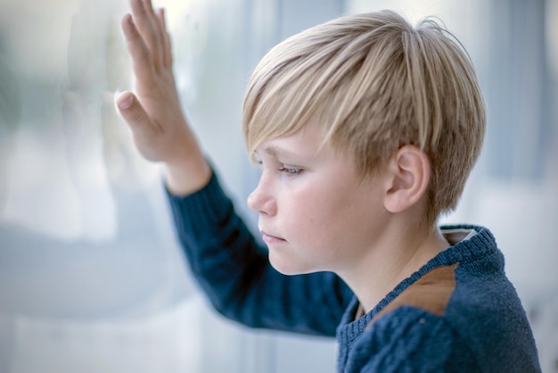 Blond teen boy looking out the window