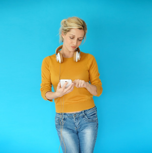 Blond woman using smartphone and headphones