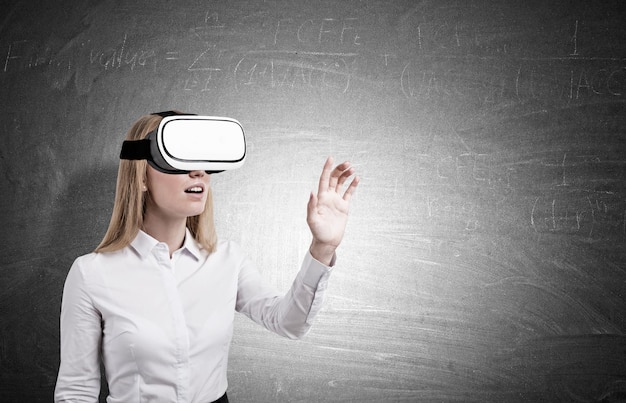 Blond woman in vr glasses near a chalkboard