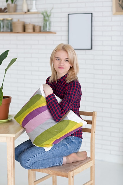 Blond woman with cushin in studio