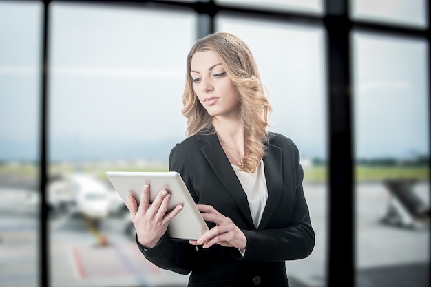 Blonde beautiful business woman working on laptop while waiting for her flight in an airport