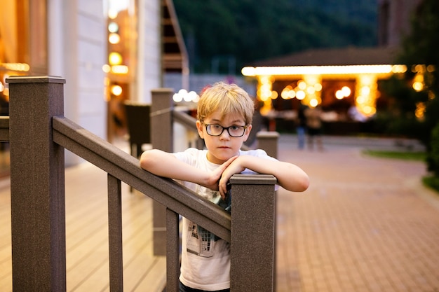 Blonde boy in the big glasses walking outside in the evening