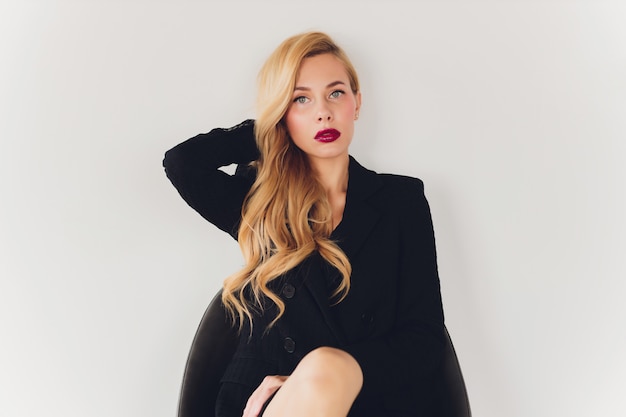 Blonde businesswoman in a black suit on a chair