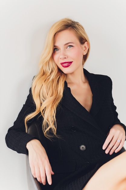 Blonde businesswoman in a black suit on a chair