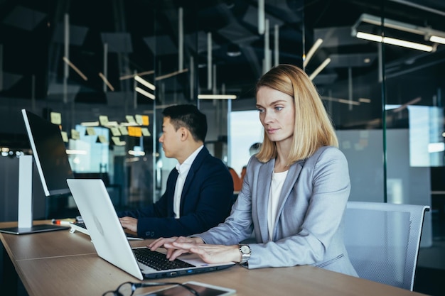 Blonde businesswoman working in modern office on laptop team of business people working together