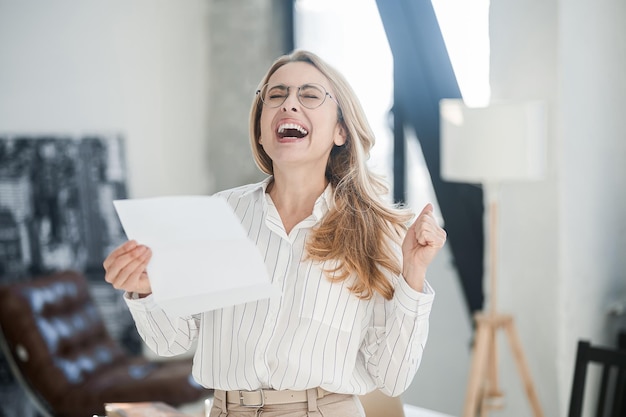 A blonde elegant woman in the offcie with documents in hands