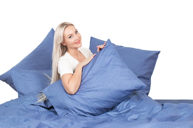 blonde girl in bed with white pillows and a blanket in a bright bedroom, home textiles