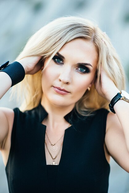 Blonde girl in a black trouser suit with blue eyes on the background of a granite quarry from gray rubble