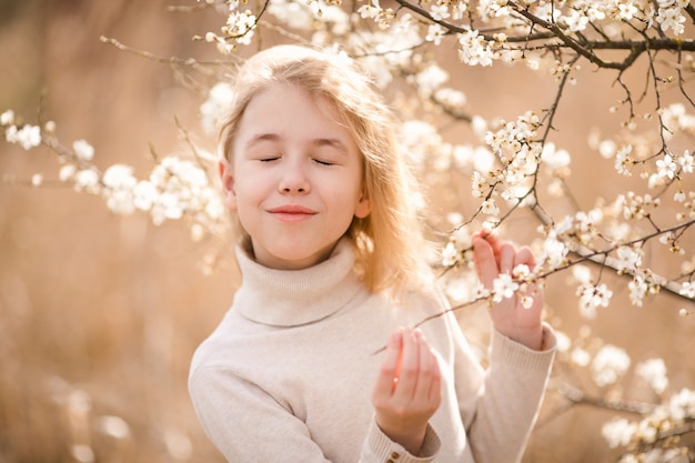 Blonde girl in the blossom garden. Spring background with white flower