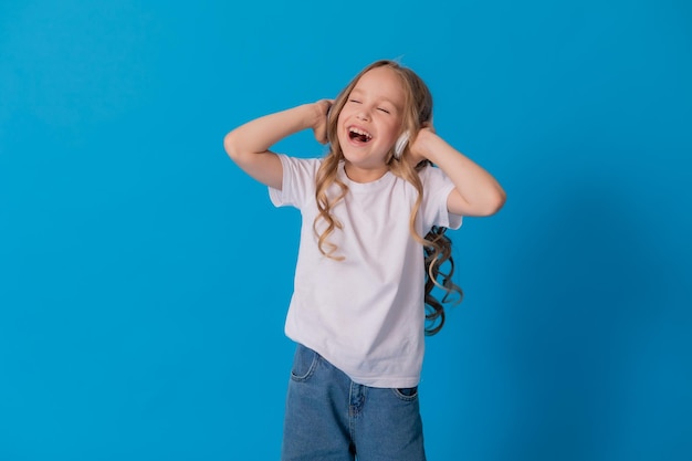 blonde girl in jeans and a white T-shirt listens to music with headphones and dances