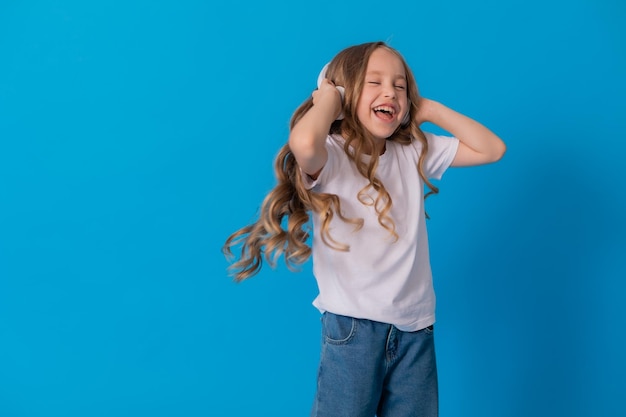 blonde girl in jeans and a white T-shirt listens to music with headphones and dances