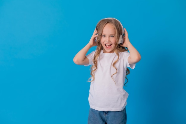 blonde girl in jeans and a white T-shirt listens to music with headphones and dances