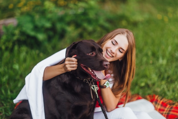 Blonde girl laughing with her dog friend in the park