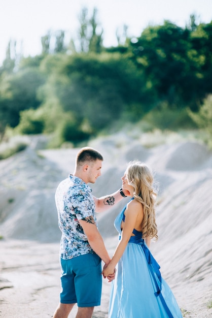 Blonde girl in a light blue dress and a guy in a light shorts and short shirt in a granite quarry