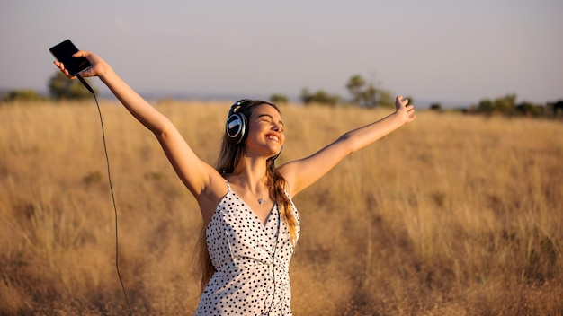 Blonde girl listening to happy music outdoors