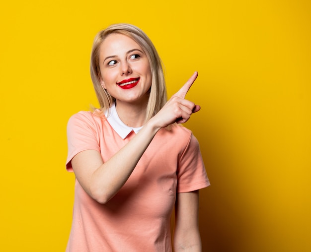 Blonde girl in pink dress show gesture on yellow space