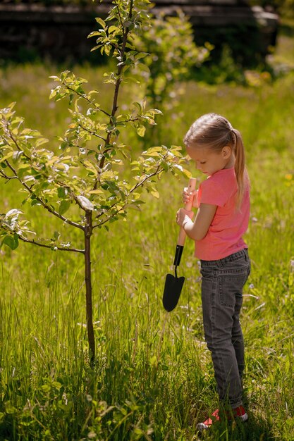 Blonde girl in pink tshirt looking busy while working in the garden