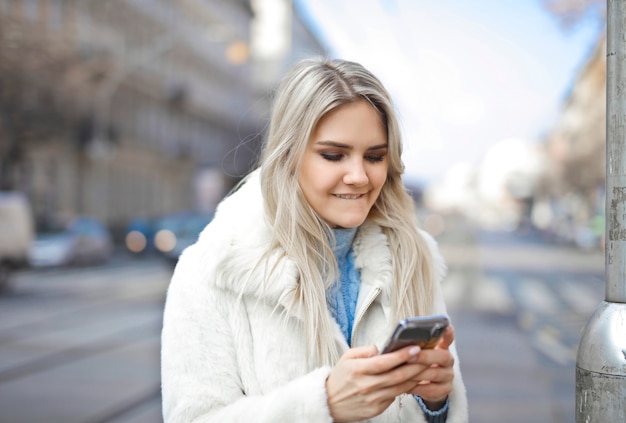 Blonde girl using a smartphone on the street