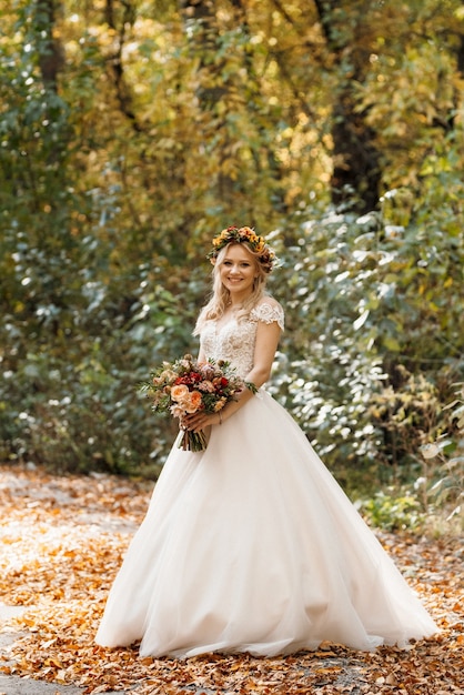 Blonde girl in a wedding dress in the autumn forest